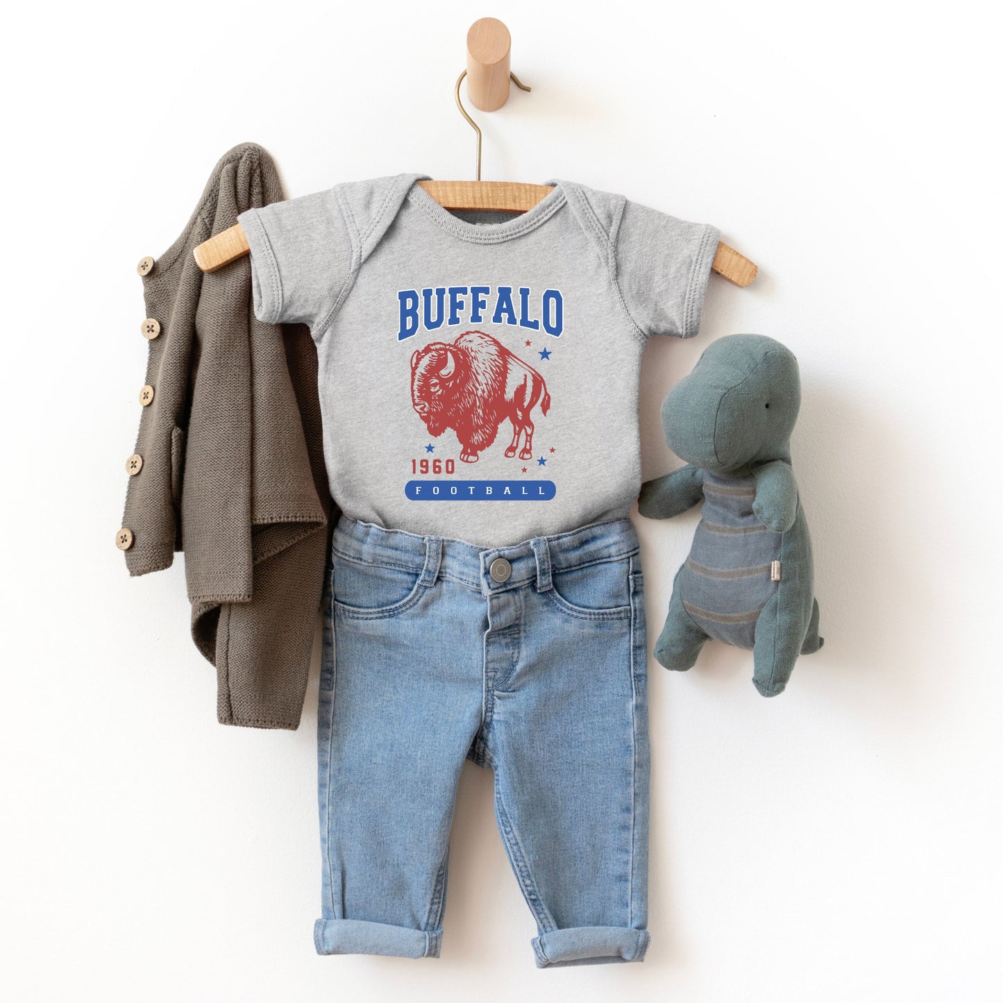 a baby boy's outfit and a teddy bear hanging on a wall