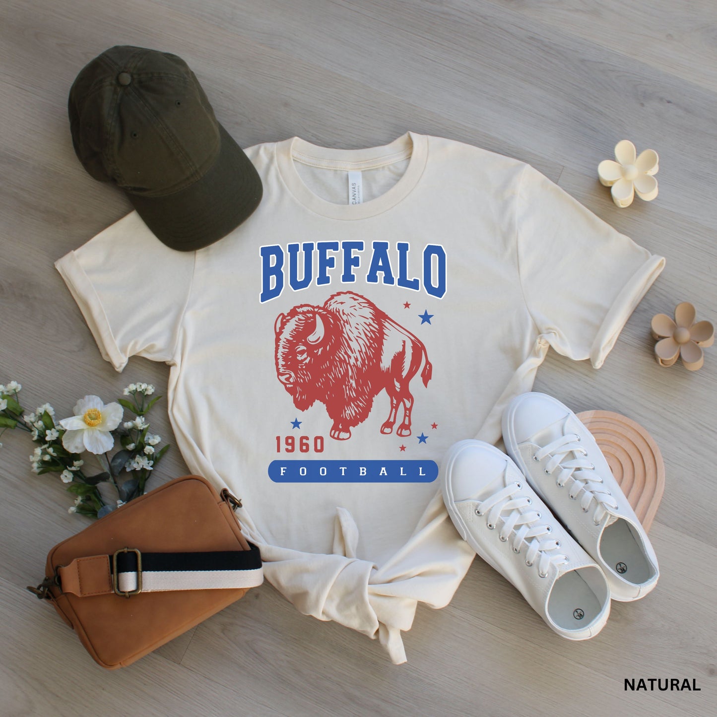 a buffalo shirt, hat, and other items laid out on a wooden floor