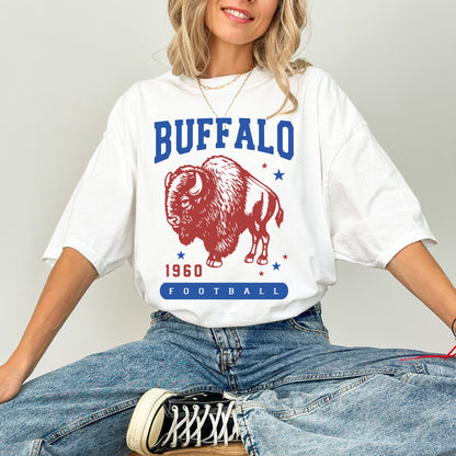 Retro-inspired graphic featuring a bold bison with ‘Buffalo Football 1960’ in classic varsity font. The red, white, and blue color scheme, paired with vintage stars, gives off a nostalgic, game-day vibe celebrating Buffalo’s heritage.