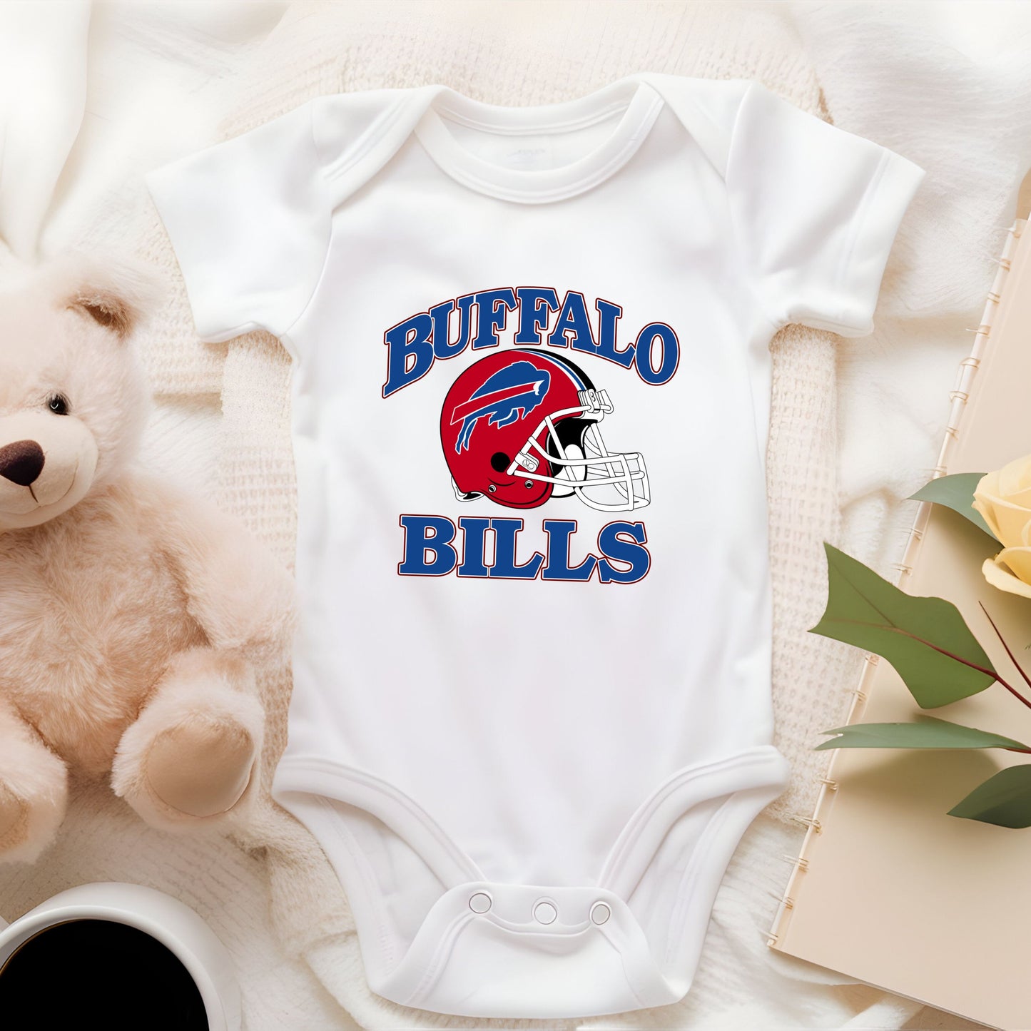 a teddy bear sitting next to a bodysuit with buffalo bills on it